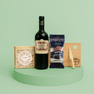 Set gourmet con vino Rutini, queso, salamín, tabla de madera y cuchillo sobre pedestal verde claro.